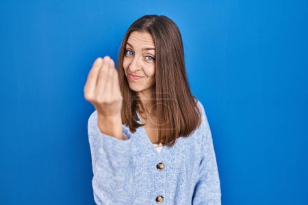 Photo for Young woman standing over blue background doing italian gesture with hand and fingers confident expression - Royalty Free Image