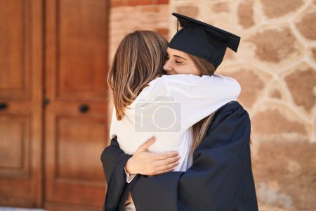 Photo for Two women mother and graduated daughter hugging each other at campus university - Royalty Free Image