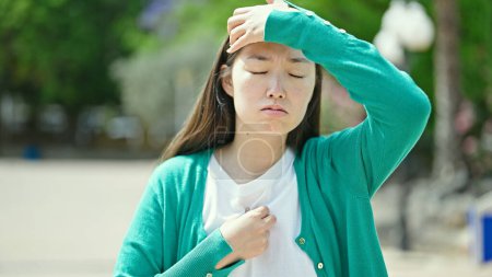 Photo for Young chinese woman suffering for headache at park - Royalty Free Image