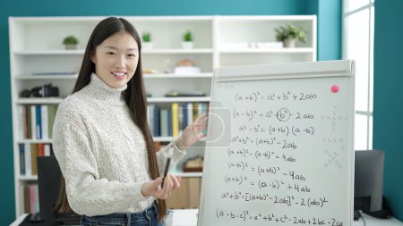 Photo for Young chinese woman student smiling confident explaining maths exercise at library university - Royalty Free Image
