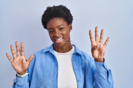 Photo for African american woman standing over blue background showing and pointing up with fingers number nine while smiling confident and happy. - Royalty Free Image