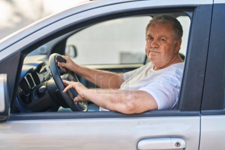 Téléchargez les photos : Moyen âge homme aux cheveux gris souriant voiture de conduite confiante à la rue - en image libre de droit