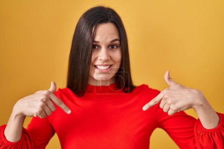 Photo for Young hispanic woman standing over yellow background looking confident with smile on face, pointing oneself with fingers proud and happy. - Royalty Free Image