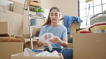 Photo for Young beautiful hispanic woman packing cardboard box at new home - Royalty Free Image