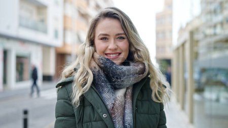 Téléchargez les photos : Jeune femme blonde souriante confiante debout dans la rue - en image libre de droit