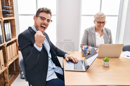 Photo for Hispanic young man working at the office screaming proud, celebrating victory and success very excited with raised arm - Royalty Free Image