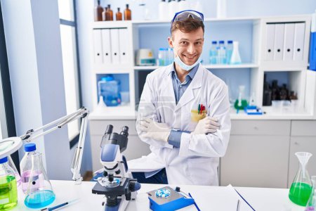 Photo for Caucasian man working at scientist laboratory happy face smiling with crossed arms looking at the camera. positive person. - Royalty Free Image