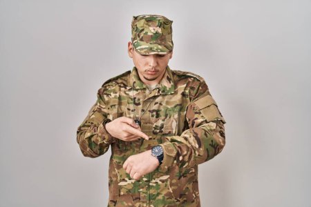 Foto de Hombre árabe joven con camuflaje uniforme del ejército comprobar la hora en el reloj de pulsera, relajado y seguro - Imagen libre de derechos