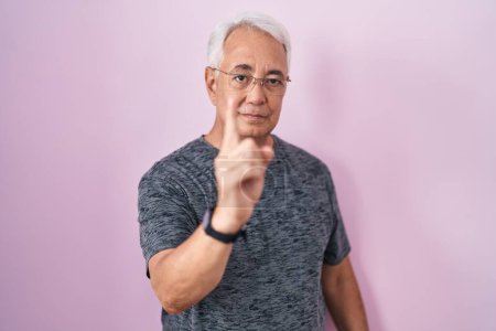 Photo for Middle age man with grey hair standing over pink background pointing with finger up and angry expression, showing no gesture - Royalty Free Image