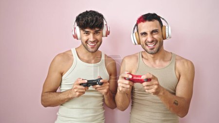 Photo for Two men smiling confident playing video game over isolated pink background - Royalty Free Image