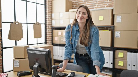 Photo for Young beautiful hispanic woman ecommerce business worker using computer standing at office - Royalty Free Image