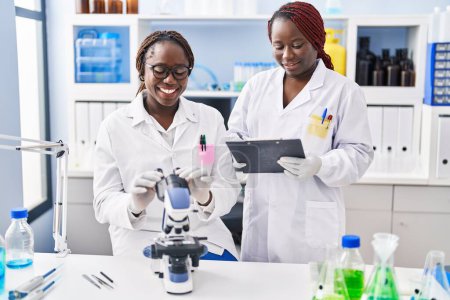 Téléchargez les photos : Des femmes scientifiques afro-américaines utilisent le microscope pour écrire des documents en laboratoire - en image libre de droit