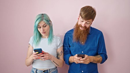 Photo for Man and woman couple using smartphones smiling over isolated pink background - Royalty Free Image