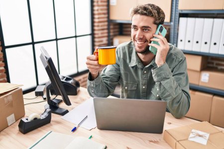 Photo for Young man ecommerce business worker talking on smartphone drinking coffee at office - Royalty Free Image