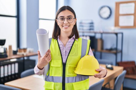 Photo for Hispanic girl architect holding build project blueprints smiling with a happy and cool smile on face. showing teeth. - Royalty Free Image