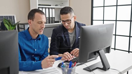 Téléchargez les photos : Deux hommes d'affaires faisant des achats avec ordinateur et carte de crédit au bureau - en image libre de droit