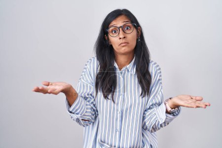 Photo for Young hispanic woman wearing glasses clueless and confused with open arms, no idea concept. - Royalty Free Image