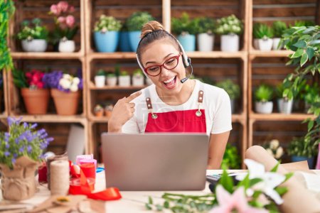 Photo for Young hispanic woman working at florist shop doing video call smiling happy pointing with hand and finger - Royalty Free Image