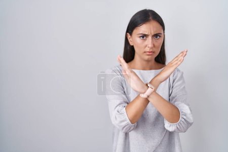 Foto de Mujer hispana joven de pie sobre fondo blanco expresión de rechazo cruzando brazos haciendo signo negativo, cara enojada - Imagen libre de derechos