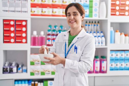 Photo for Young woman pharmacist smiling confident working at pharmacy - Royalty Free Image