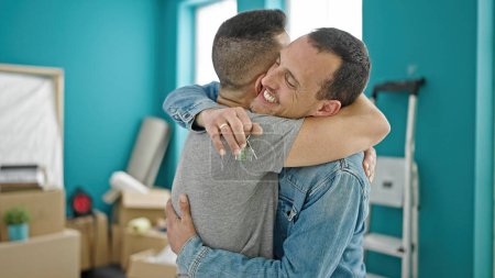 Photo for Two men smiling confident hugging each other at new home - Royalty Free Image