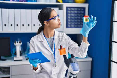 Photo for Young african american woman scientist analysing urine test tube using touchpad at laboratory - Royalty Free Image