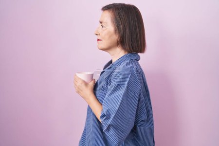 Photo for Middle age hispanic woman drinking a cup coffee looking to side, relax profile pose with natural face and confident smile. - Royalty Free Image