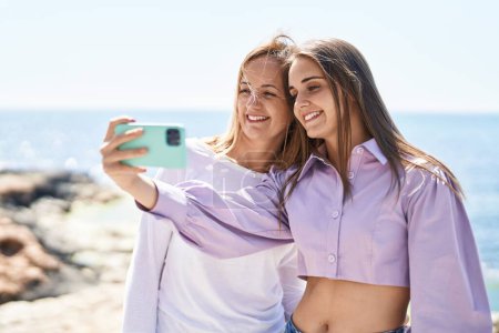 Téléchargez les photos : Two women mother and daughter make selfie by smartphone at seaside - en image libre de droit