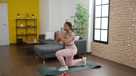 Téléchargez les photos : Femme afro-américaine entraînement jambes exercice à la maison - en image libre de droit