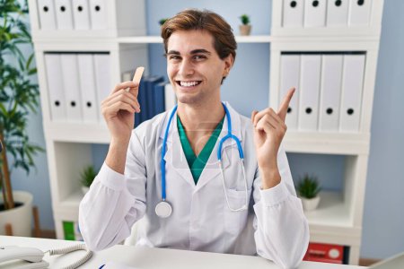 Téléchargez les photos : Jeune homme médecin tenant pansement sourire heureux pointant avec la main et le doigt sur le côté - en image libre de droit