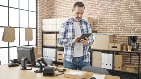 Téléchargez les photos : Middle age man ecommerce business worker using touchpad at office - en image libre de droit