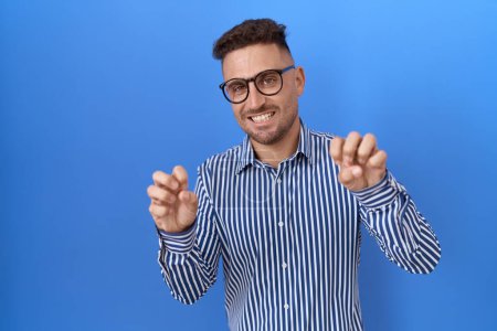 Photo for Hispanic man with beard wearing glasses smiling funny doing claw gesture as cat, aggressive and sexy expression - Royalty Free Image