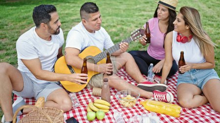 Photo for Group of people having picnic sitting on grass at park - Royalty Free Image
