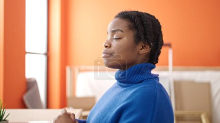 Téléchargez les photos : Femme afro-américaine respirant les yeux fermés à la nouvelle maison - en image libre de droit