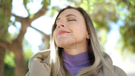 Téléchargez les photos : Jeune femme blonde respirant les yeux fermés au parc - en image libre de droit