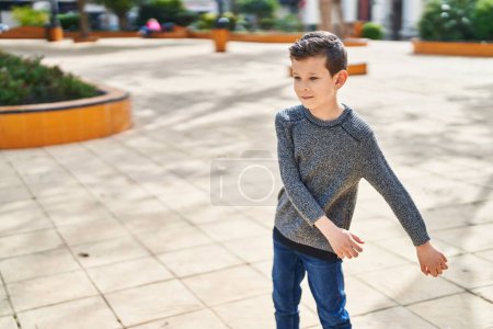 Téléchargez les photos : Enfant blond souriant dansant avec confiance au parc - en image libre de droit
