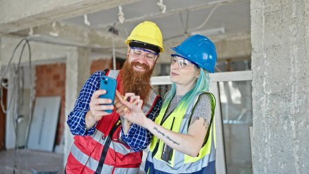 Téléchargez les photos : Constructeurs hommes et femmes utilisant un smartphone travaillant sur le chantier de construction - en image libre de droit