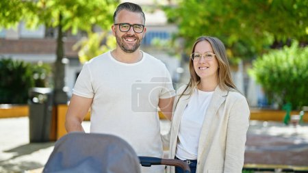 Photo for Family of three walking with a baby cart at the park - Royalty Free Image