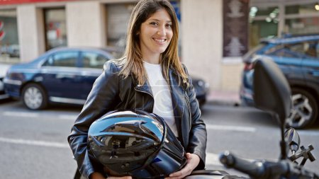 Téléchargez les photos : Jeune femme blonde souriant confiant assis sur la moto à la rue - en image libre de droit
