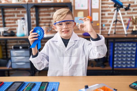 Foto de Pequeño chico caucásico en el laboratorio científico de la escuela ganando el primer premio haciendo signo ok con los dedos, sonriendo gesto amistoso excelente símbolo - Imagen libre de derechos