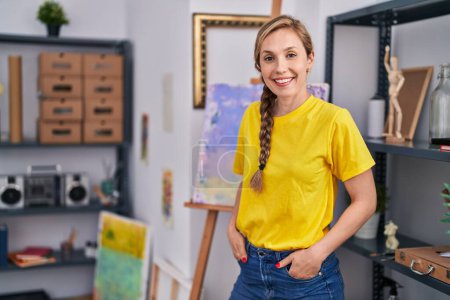 Téléchargez les photos : Jeune artiste blonde souriante confiante au studio d'art - en image libre de droit