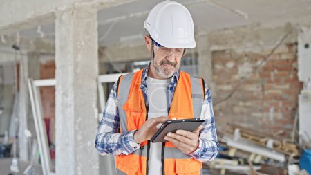 Photo for Middle age man builder using touchpad at construction site - Royalty Free Image