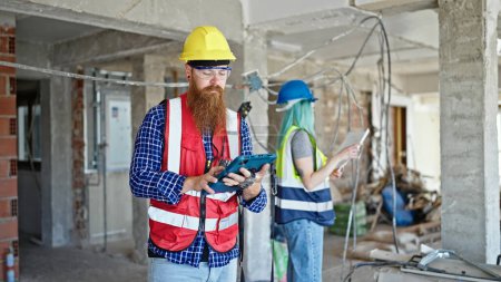 Téléchargez les photos : Constructeurs hommes et femmes utilisant le projet de maison de lecture tactile sur le chantier de construction - en image libre de droit