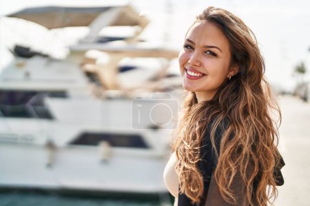 Foto de Joven hermosa mujer hispana sonriendo confiada de pie en la playa - Imagen libre de derechos