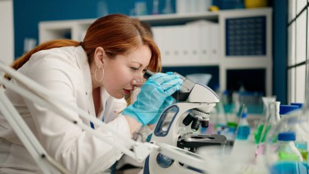 Téléchargez les photos : Homme et femme portant un uniforme de scienciste au microscope en laboratoire - en image libre de droit