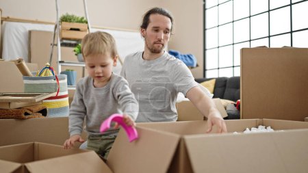 Photo for Father and son unpacking cardboard box at new home - Royalty Free Image