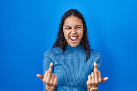 Photo for Young brazilian woman standing over blue isolated background showing middle finger doing fuck you bad expression, provocation and rude attitude. screaming excited - Royalty Free Image