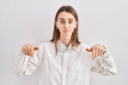 Photo for Young caucasian woman standing over isolated background pointing down looking sad and upset, indicating direction with fingers, unhappy and depressed. - Royalty Free Image