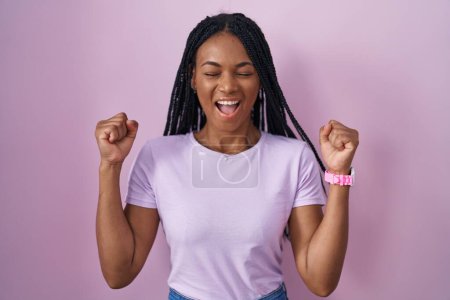 Photo for African american woman with braids standing over pink background excited for success with arms raised and eyes closed celebrating victory smiling. winner concept. - Royalty Free Image