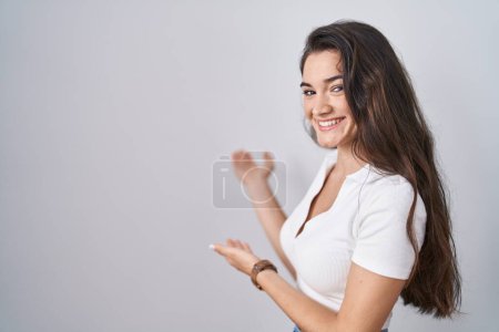Photo for Young teenager girl standing over white background inviting to enter smiling natural with open hand - Royalty Free Image